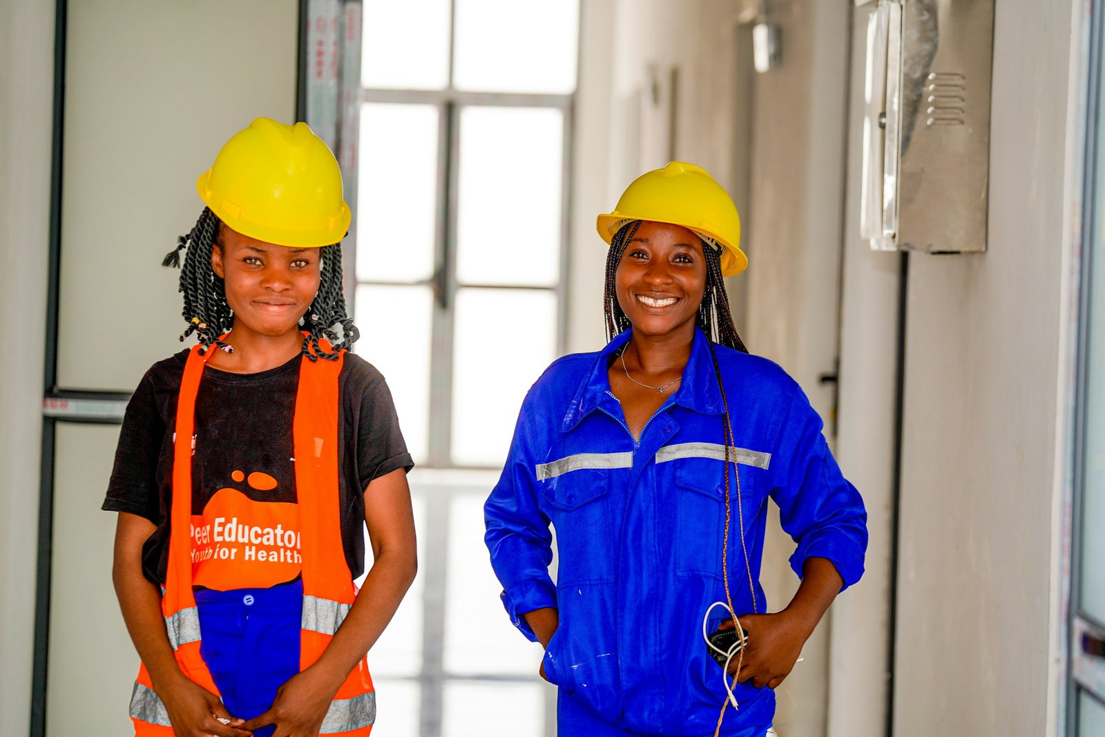 Two women in hard hats and hi-vis workwear smiling on a solar-plant construction site