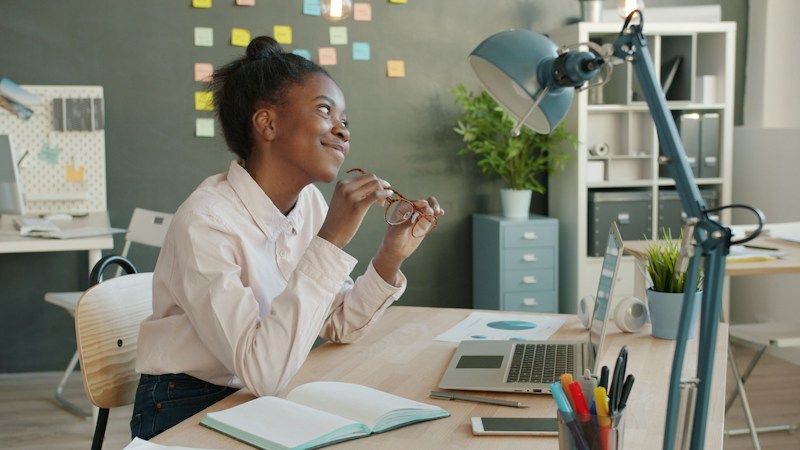 A young professional working on a laptop at her office desk