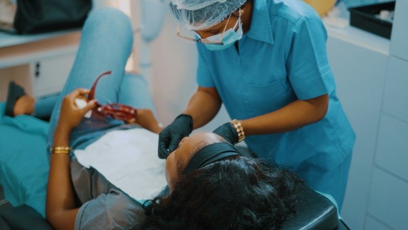 A dentist and assistant treating a patient in a dental chair