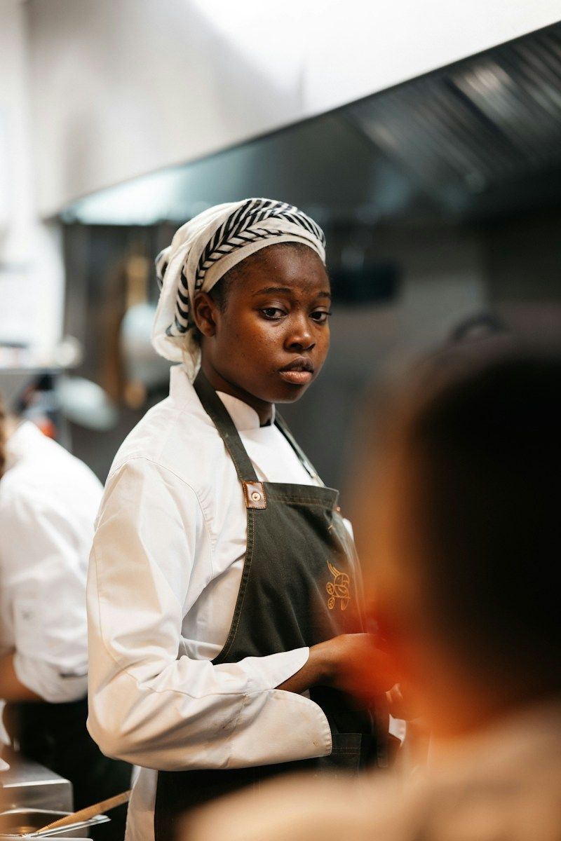 A chef in whites plating food in a restaurant kitchen